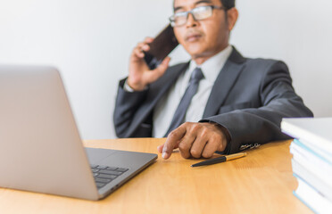 Business man looking on monitor laptop and using smartphone with spread the hand on workplace