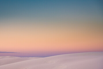Fototapeta na wymiar Ridges of Sand Dunes On The Horizon With Pastel Colors Fading Together At Sunset