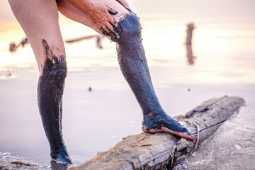 An elderly woman smears her feet with curative mud at the Pink Lemur Lake on the Arabat Spit in Ukraine. A lake with salt crystals and healing mud. Dead sea analog