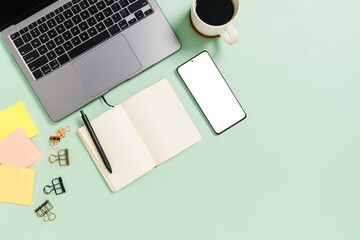 Creative flat lay photo of workspace desk. Top view office desk with laptop, coffee cup and open mockup black notebook on pastel green color background. Top view mock up with copy space photography.