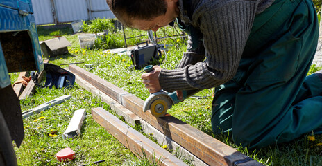 Man grinds a metal product with angle grinder outdoors. Metal processing with angle grinder. Sparks from the grinding wheel