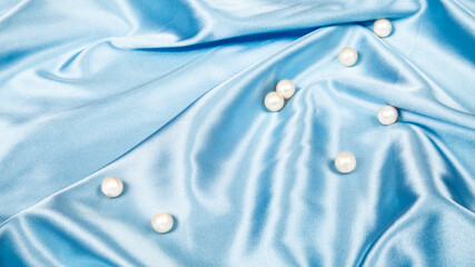 pearls on light blue luxury satin fabric. Background. elegant wallpaper. Abstract wallpaper for the...