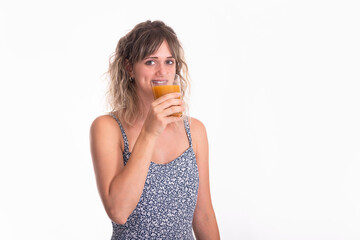 Healthy adult woman drinking a fruit juice while looking at camera on a white background