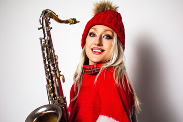 Beautiful happy smiling young woman in red holding saxophone, a Christmas poster