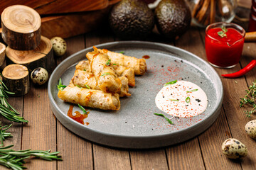 Turkish cigar shaped rolls boreks with sauce on wooden background