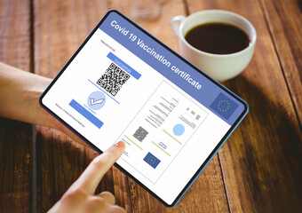Hands of woman using tablet with covid vaccination certificate and qr code on screen