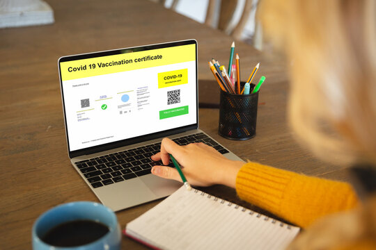 Caucasian woman using laptop with covid vaccination certificate and qr code on screen