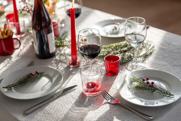 winter holidays, dinner party and celebration concept - christmas table serving with candles, crockery and wine at home