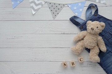 Baby boy background, childhood, kids activity concept, flat lay composition with toy bear, wooden cubes, blue denim and flag banner.