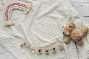 Baby waiting, pregnancy announcement background, flat lay with cozy blanket, boho rainbow decoration, wooden blocks and toy bear.