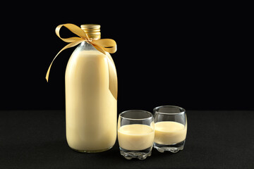Homemade eggnog in bottle and two glasses with Christmas cookies