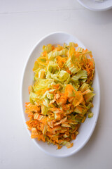 Zucchini flowers or courgette flowers on a white plate background. over white wooden table.  Organic food.