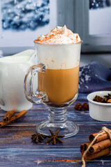 Hot coffee latte with cinnamon sticks, sprinkled with cinnamon. Christmas decorations, branches of a Christmas tree. Holiday concept New Year.