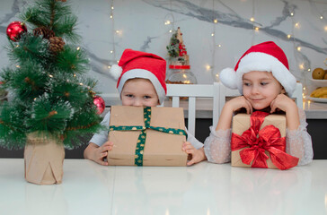 Merry Christmas! Cute little kids are opening magical Christmas gifts at home in the kitchen. Decorated living room for holiday. The concept of holidays, Christmas and childhood. Selective focus