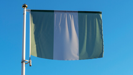 National flag of Nigeria on a flagpole in front of blue sky with sun rays and lens flare. Diplomacy concept.