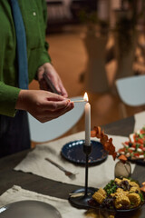Close-up of man lighting candle on dining table and preparing for dinner party