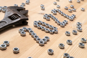 Number 2022 is lined with metal nuts on a wooden table next to a large, old wrench. Concept of preparing for the New Year. 