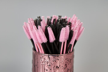 A jar with brushes for eyelashes on a gray background. Cosmetic accessories for eyelash extensions
