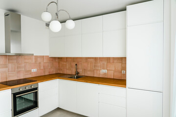 Fototapeta na wymiar Modern kitchen interior with furniture and electrical appliances. Trendy stylish kitchen in white, beige-rose and wooden clear tones.