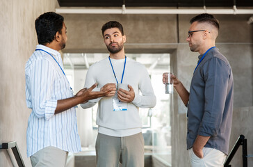 Obraz premium business, people and corporate concept - businessmen or male colleagues with name tags drinking takeaway coffee at office