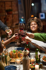 Happy people toasting with glasses of red wine while celebrating at dining table