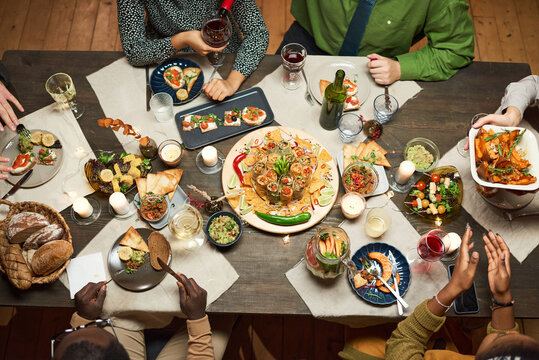High angle view of dining table with delicious dish and appetizers with people sitting at the table
