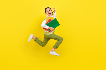 Full length body size view of attractive funny crazy girl jumping running holding book isolated on bright yellow color background