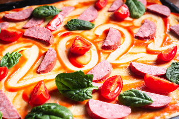 Cooking New Year's pizza with the numbers 2022 with tomatoes, herbs and sausage.
