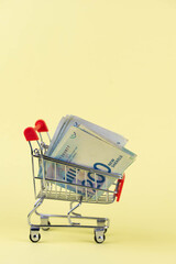Israel money shekel banknotes in shopping cart on yellow background. Exchange Rates and buy sell...