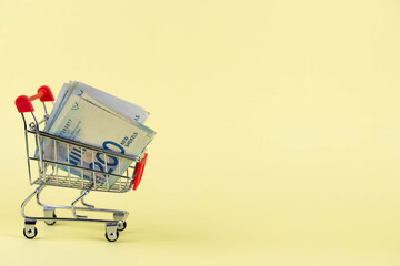 Israel money shekel banknotes in shopping cart on yellow background. Exchange Rates and buy sell...