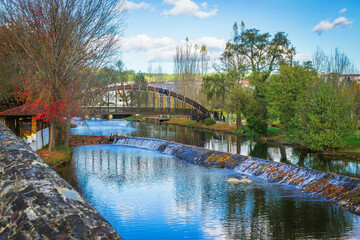 Beautiful park with river and stone bridge in the village of Serta - Portugal. Autumn folliage trees reflecting on the water. Roman ancient bridge over the river