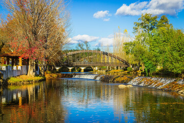 Beautiful park with river and stone bridge in the village of Serta - Portugal. Autumn folliage trees reflecting on the water. Roman ancient bridge over the river