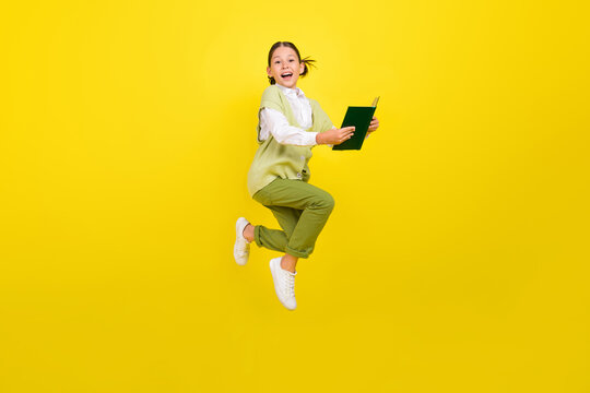 Full length body size view of attractive cheery trendy smart girl jumping reading book isolated over bright yellow color background