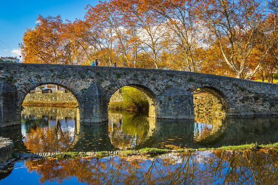 Beautiful park with river and stone bridge in the village of Serta - Portugal. Autumn folliage trees reflecting on the water. Roman ancient bridge over the river