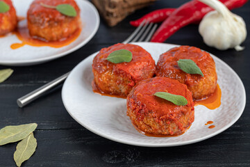 Fish cakes in tomato juice with onions and carrots. Diet. Sauerkraut. On a dark wooden background.