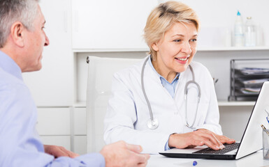 Doctor interviews mature patient and fills data in computer database