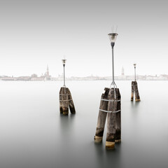 Drei Lampen am Ufer der Lagunenstadt Venedig, Italien, mit der Skyline Venedis im Hintergrund. - 471096501