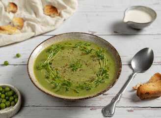 Green fresh pea soup with cream and micro greens
