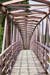 An arched pedestrian bridge over the river with a wooden deck - 471096582