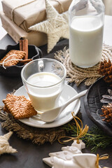 А bottle and a glass of milk on a table decorated with Christmas decor