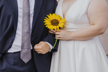 bride and groom holding hands with sunflower 