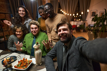 Portrait of group of happy friends smiling at camera while sitting at dining table in the living room