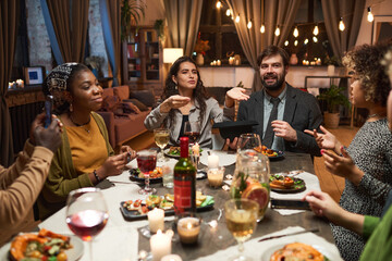 Group of young people playing the game during a dinner at the table