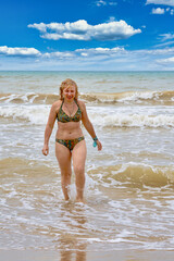 A woman in a swimsuit with white long hair comes out of the sea
