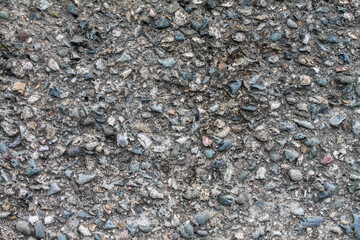 Textured background grey concrete wall with splashes of small pebbles.