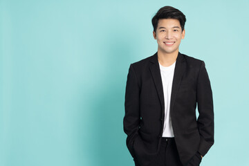 Smiling young Asian businessman in black suit isolated on green background - 471101106