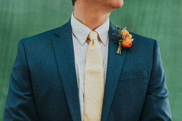 groom in suit with orange boutonniere