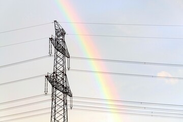 Electricity pylons with rainbow in background, global energy crisis, renewable energy and grid...