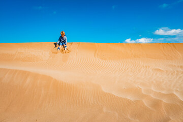 A child played on the sand dunes having fun with freedom, negative space and copy space and intense colors.