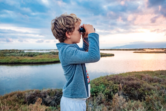 A young boy observes birds with binoculars in a nature park during his nature vacation.